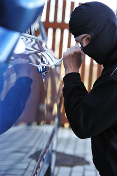 Young man in mask trying to steal a car