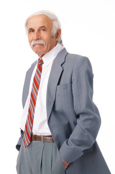Portrait of an elder man standing with his hands in his pockets.