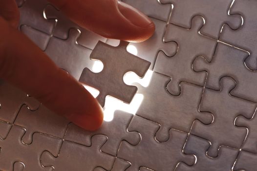 Hand placing missing puzzle piece with shallow DOF