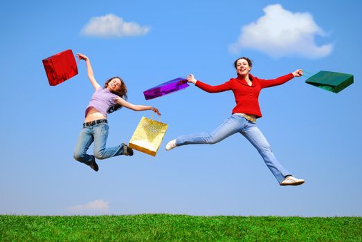 Girls jumping with bags against blue sky