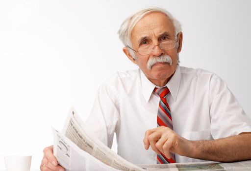 Portrait of an elder man holding an newspaper and looking at you.