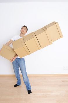 Young man carrying and dropping his stack of moving boxes