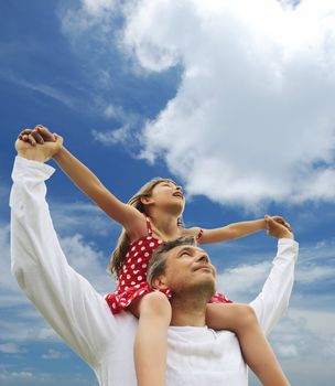 Father and daughter against sky 