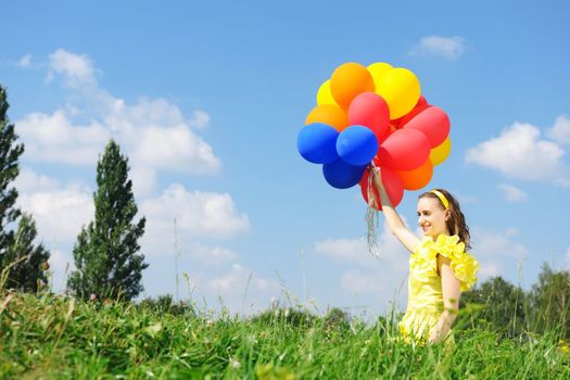 Girl holding balloons against sky