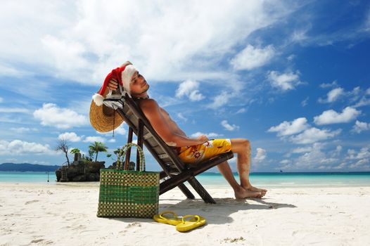 Man relaxing on the beach in santa's hat