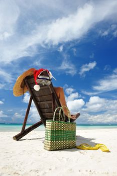 Woman relaxing on the beach in santa's hat