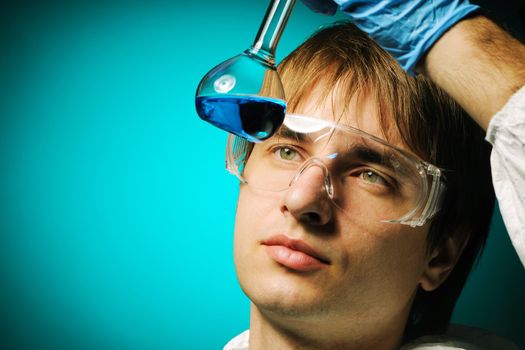 Scientist in protective wear and glasses looking at chemical flask