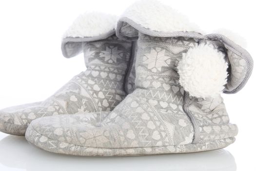 Comfortable warm furlined slippers or boots decorated with a pompom for keeping warm in cold winter weather on a white studio background 