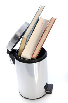 Cylindrical metal waste paper bin filled with hardcover books possibly from a student venting his or her frustration with the education system Cylindrical metal waste paper bin filled with hardcover books possibly from a student venting his or her frsutration with the education system 
