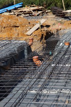 Underlying structure of a new cement floor showing steel reinforcing rods, waterproofing plastic and plumbing outlets ready to pour the overlying cement Underlying structure showing steel reinforcing rods, waterproofing plastic and plumbing outlets ready to pour the overlying cementof a new cement floor 