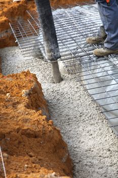 A workman stands guiding the flow of the ready mix cement while pouring the foundation of a new home on a building site 
