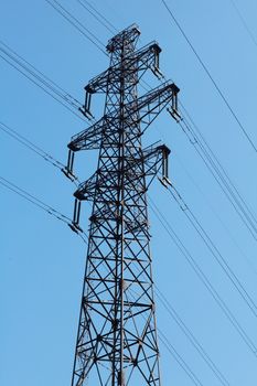 Power lines and electricity pylon  against blue sky