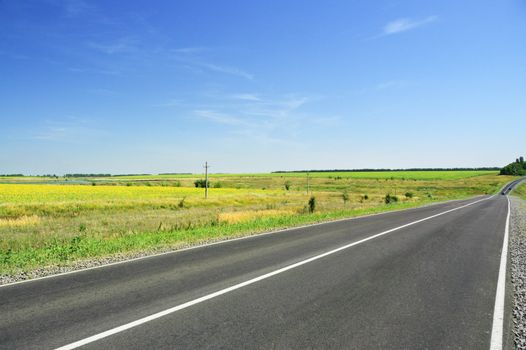 Road and green field on a background of blue sky.