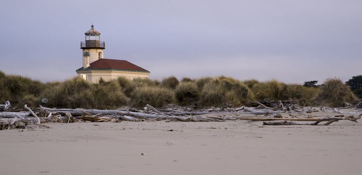 Beach driftwood at low tide in front of Coquille River Lighthouse in Oregon