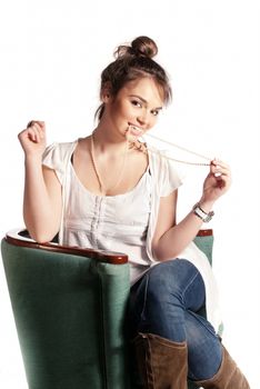 Beautiful girl posing with a necklace in a green chair isolated on white