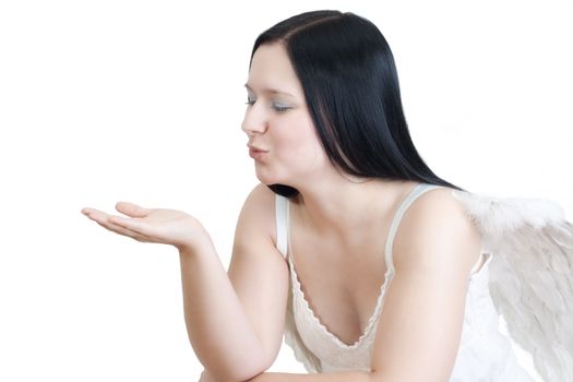 Young blackhaired woman with angel wings blowing a kiss -  isolated on white background