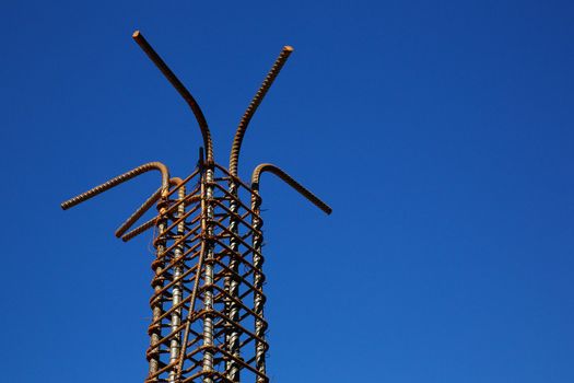 Rusted steel rebar pillar against deep blue sky