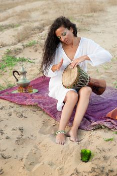 Female playing a djembe in an African setting