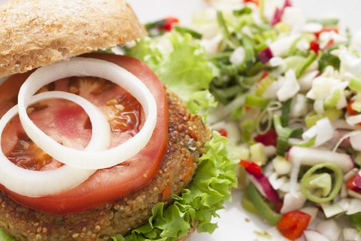Delicious and healthy quinoa burger topped with a tomato slice and onions