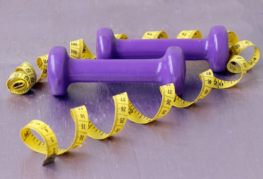 dumbbells and tailoring meter on a purple background