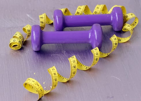 dumbbells and tailoring meter on a purple background
