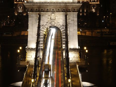 Chain bridge at night time with cars.