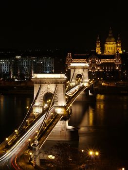 Chain bridge at night time with cars.