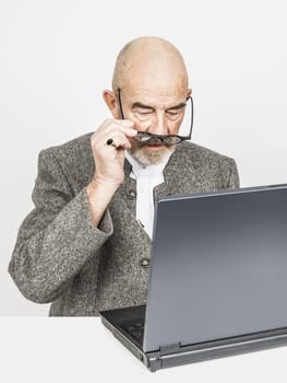 An old man with a grey beard and a computer