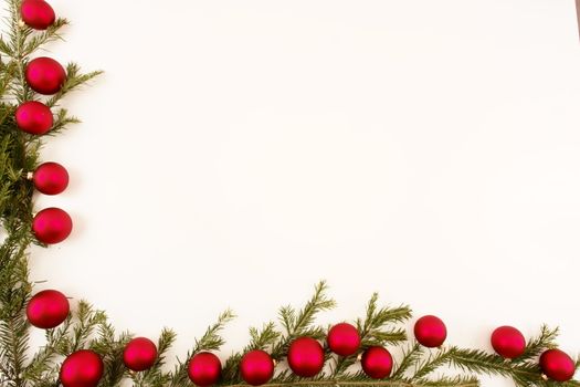 Border of red christmas garland with baubles and ribbons on white.