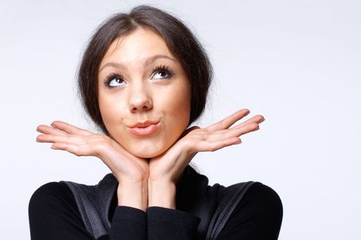 Portrait of a beautiful happy young girl looking away and holding her open palms under her chin