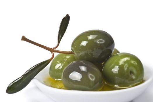 Green olives in a china spoon over a white background
