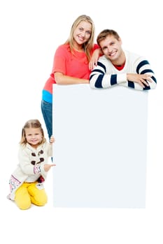 Portrait of happy family presenting blank whiteboard. Studio shot
