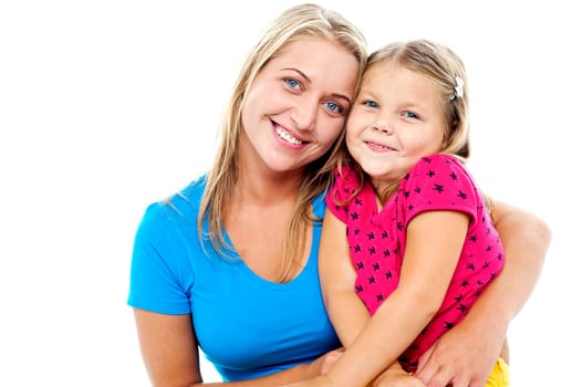 Adorable mom and daughter posing together. Indoor studio shot