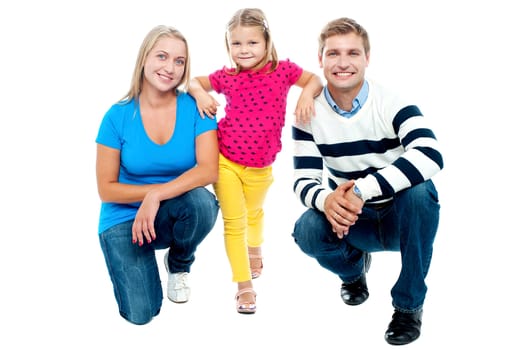 Trendy couple squatting with girl child in between. Studio shot