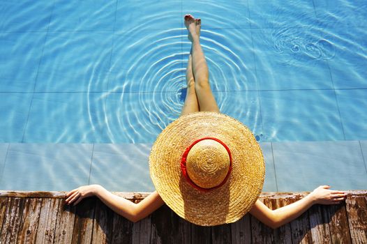 Woman in hat relaxing at the pool 