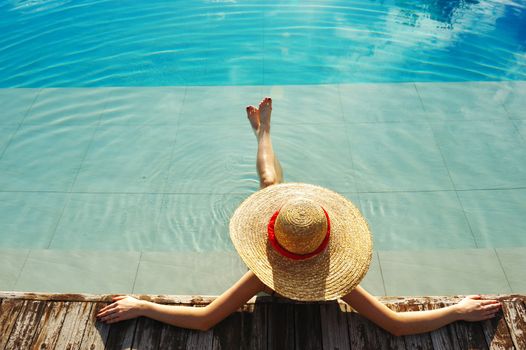 Woman in hat relaxing at the pool 