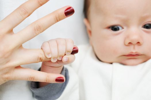 Newborn baby holding mother's finger