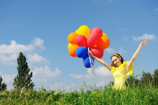 Girl holding balloons against sky