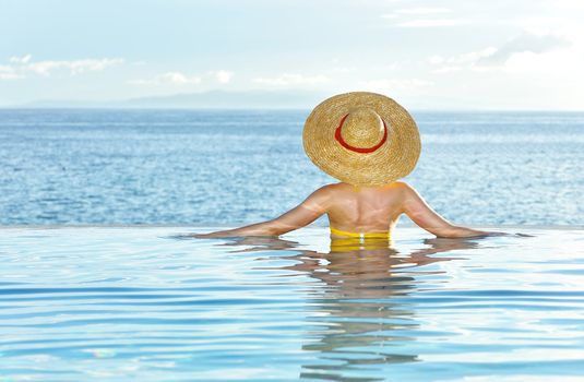 Woman in hat relaxing at the pool 