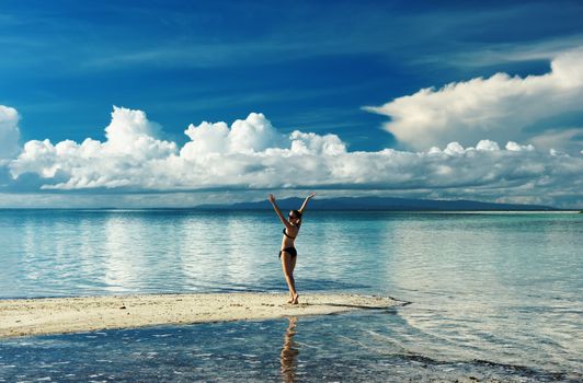 Girl on a tropical beach with outstretched arms