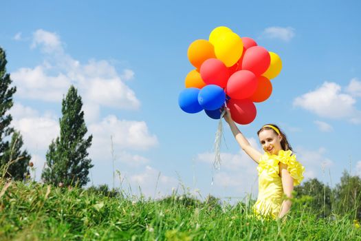 Girl holding balloons against sky