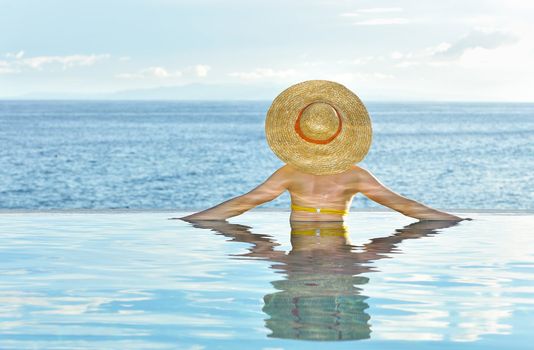 Woman in hat relaxing at the pool 