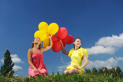 Girls holding balloons against sky
