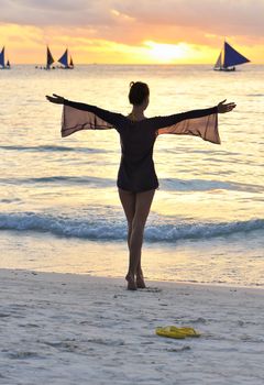 Girl on a beach at sunset with outstretched arms