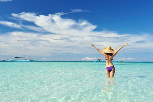 Girl on a tropical beach with outstretched arms