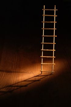 Escape abstract. Wooden ladder with shadow on dark background