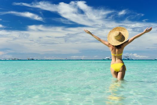 Girl on a tropical beach with outstretched arms