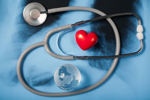 Stethoscope, glass globe earth and red heart on X-ray
