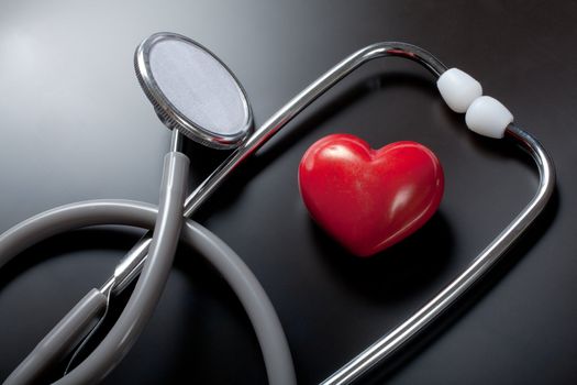 Stethoscope & red heart on black background