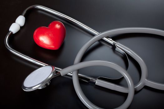 Stethoscope & red heart on black background